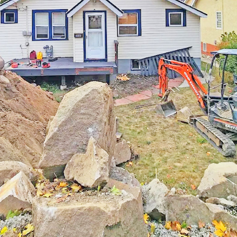 Orange Kubota excavator digging a home foundation and performing precise site grading next to a concrete foundation wall.