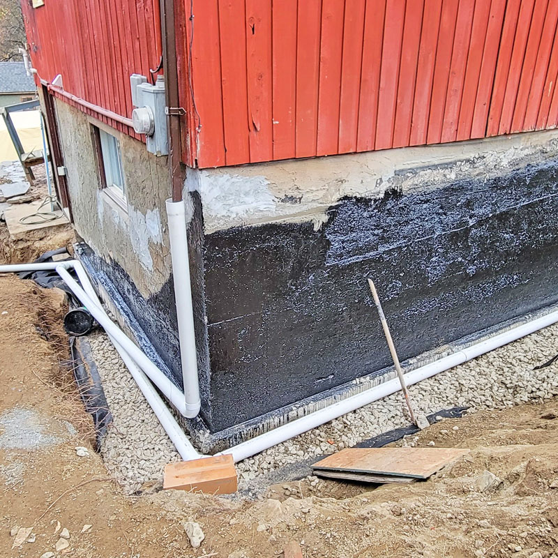 Exterior residential basement foundation waterproofing membrane and dimple board installation by a contractor in Nelson.<br />