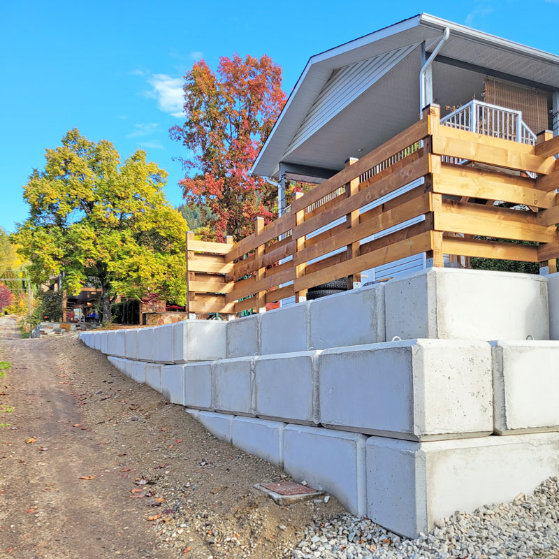 Custom hard landscaping featuring natural stone steps and rock-faced retaining tiers on a steep Kootenay property.
